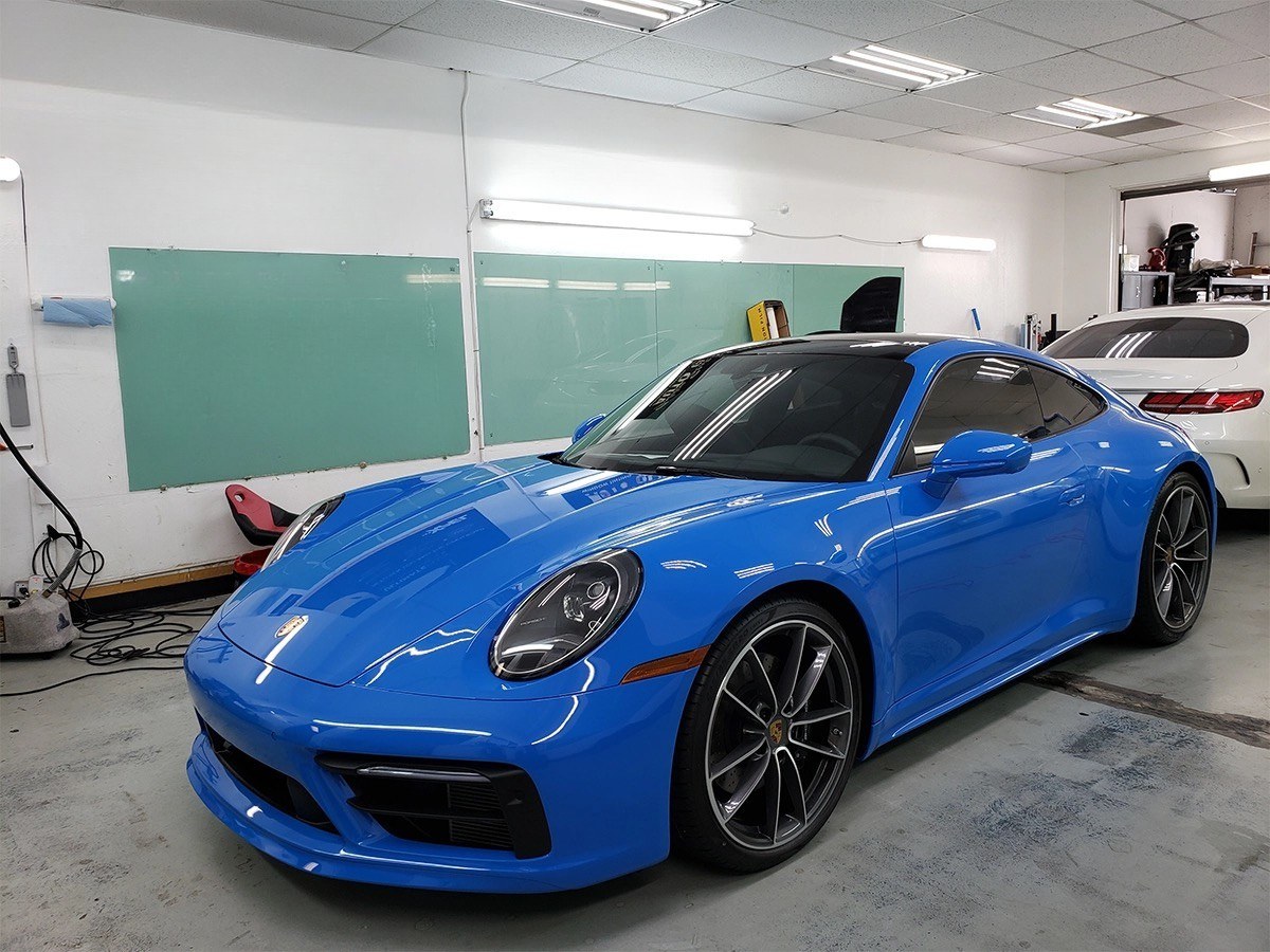 Window tint film being applied to a car in a shop bay
